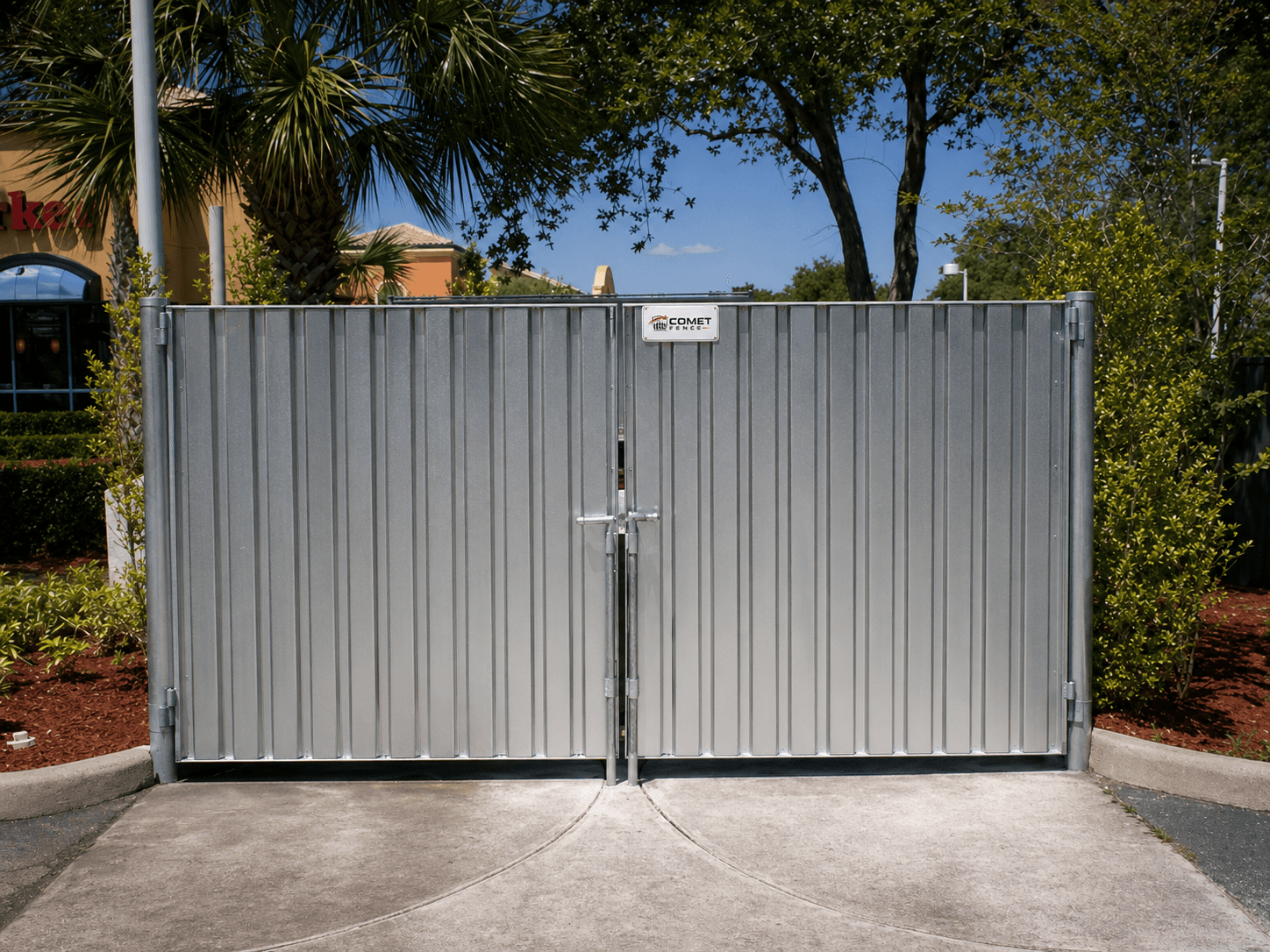 Chain link dumpster enclosure with double swing gates at a commercial site
