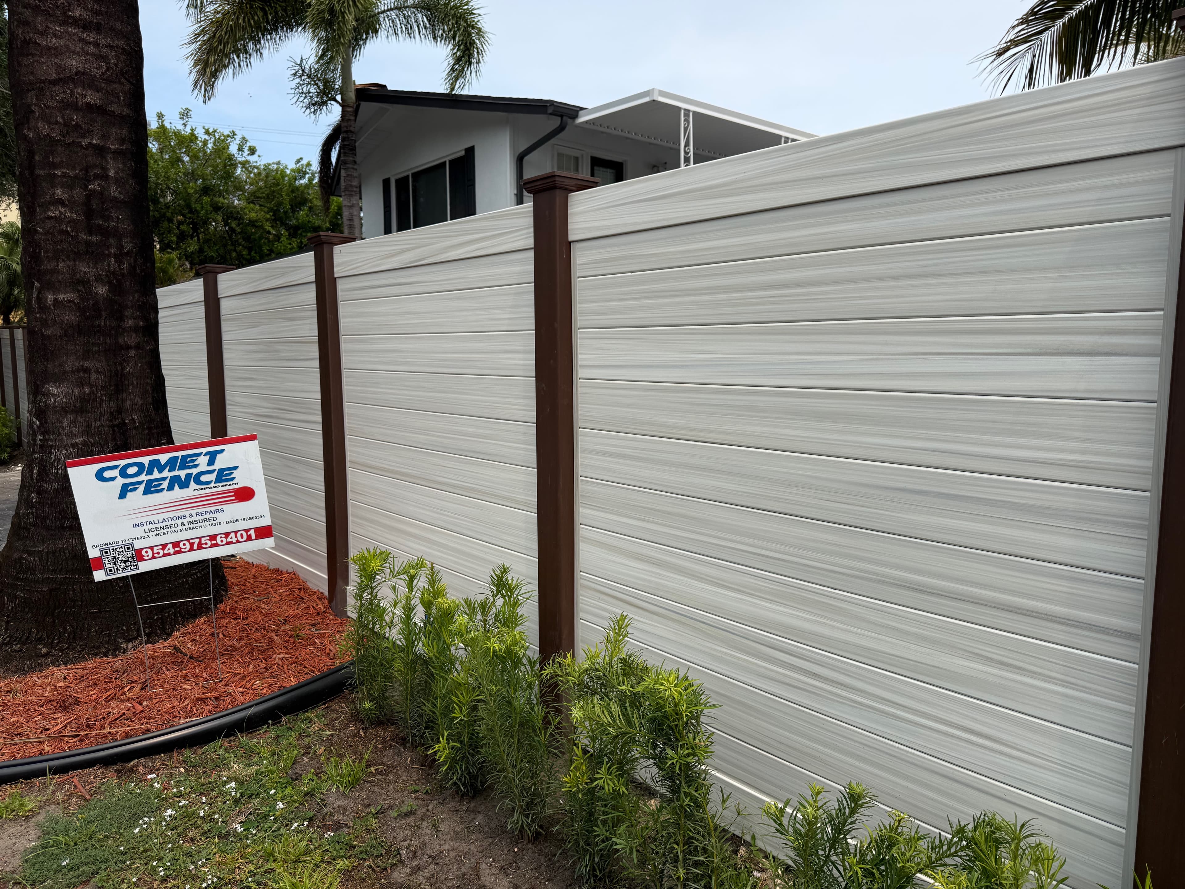 Two-tone horizontal privacy fence with Comet Fence yard sign at a residential installation