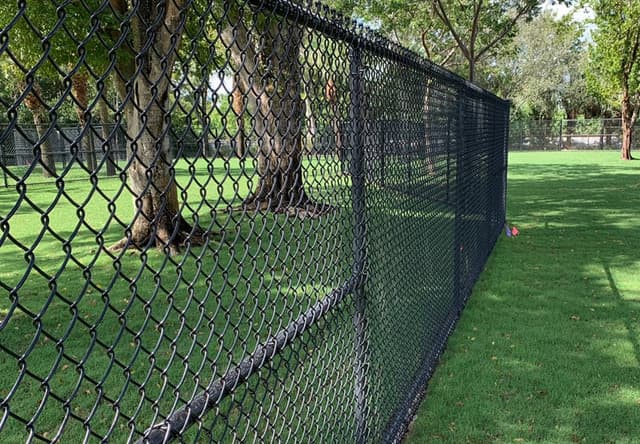 Galvanized chain link residential yard fence with greenery