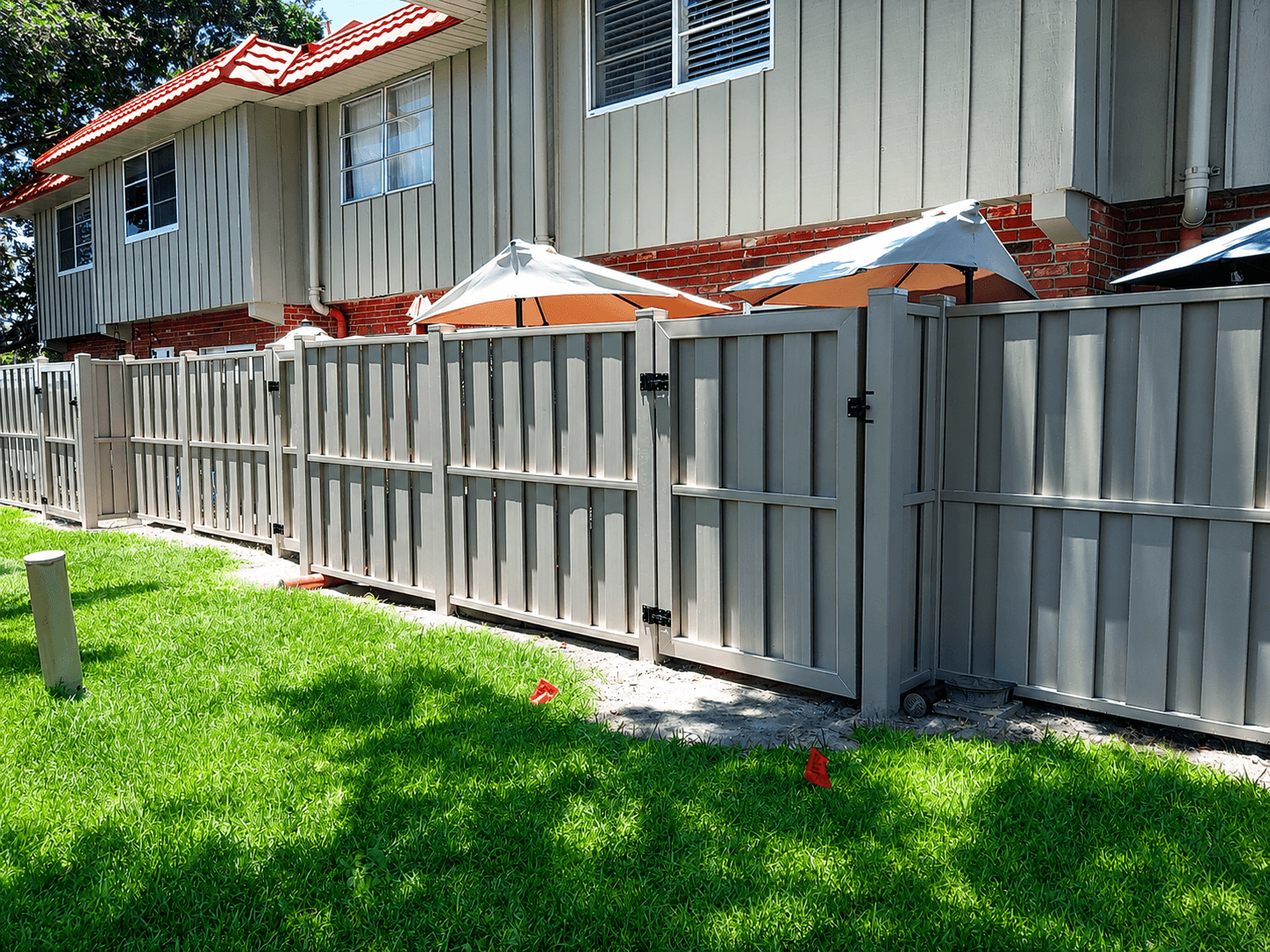 Tan vinyl shadowbox privacy fence with walk gate and black hardware at a residential property