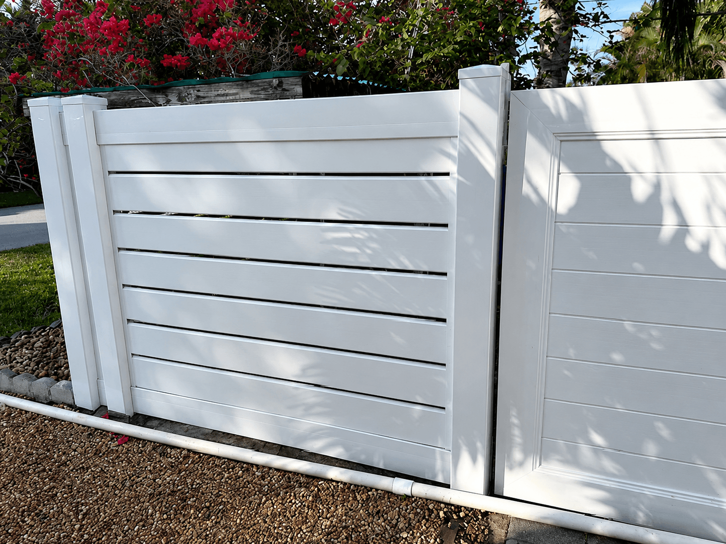 White vinyl horizontal-slat fence panel with bougainvillea and backyard landscaping