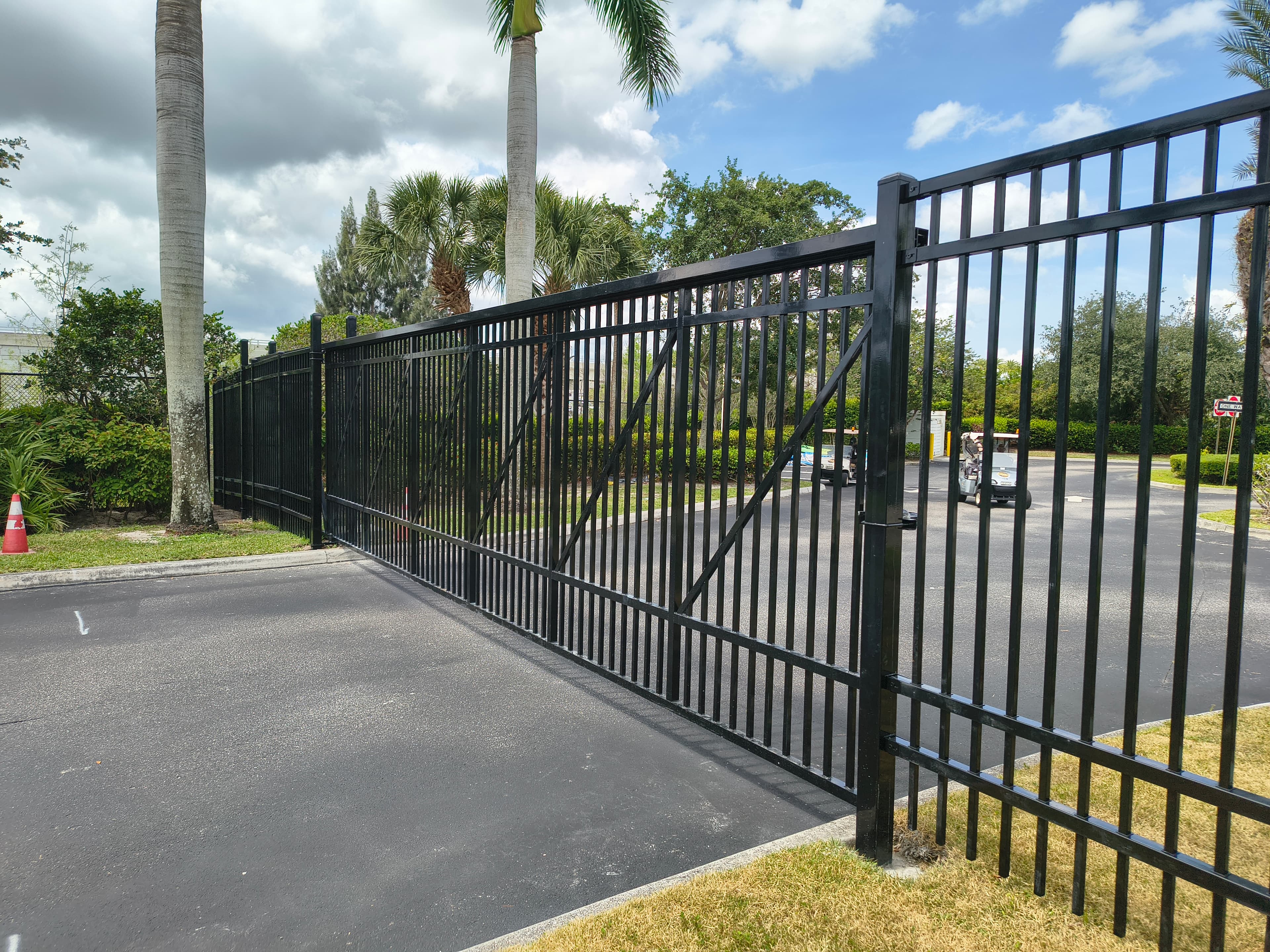 Black metal sliding cantilever gate and matching perimeter fence at a property entrance