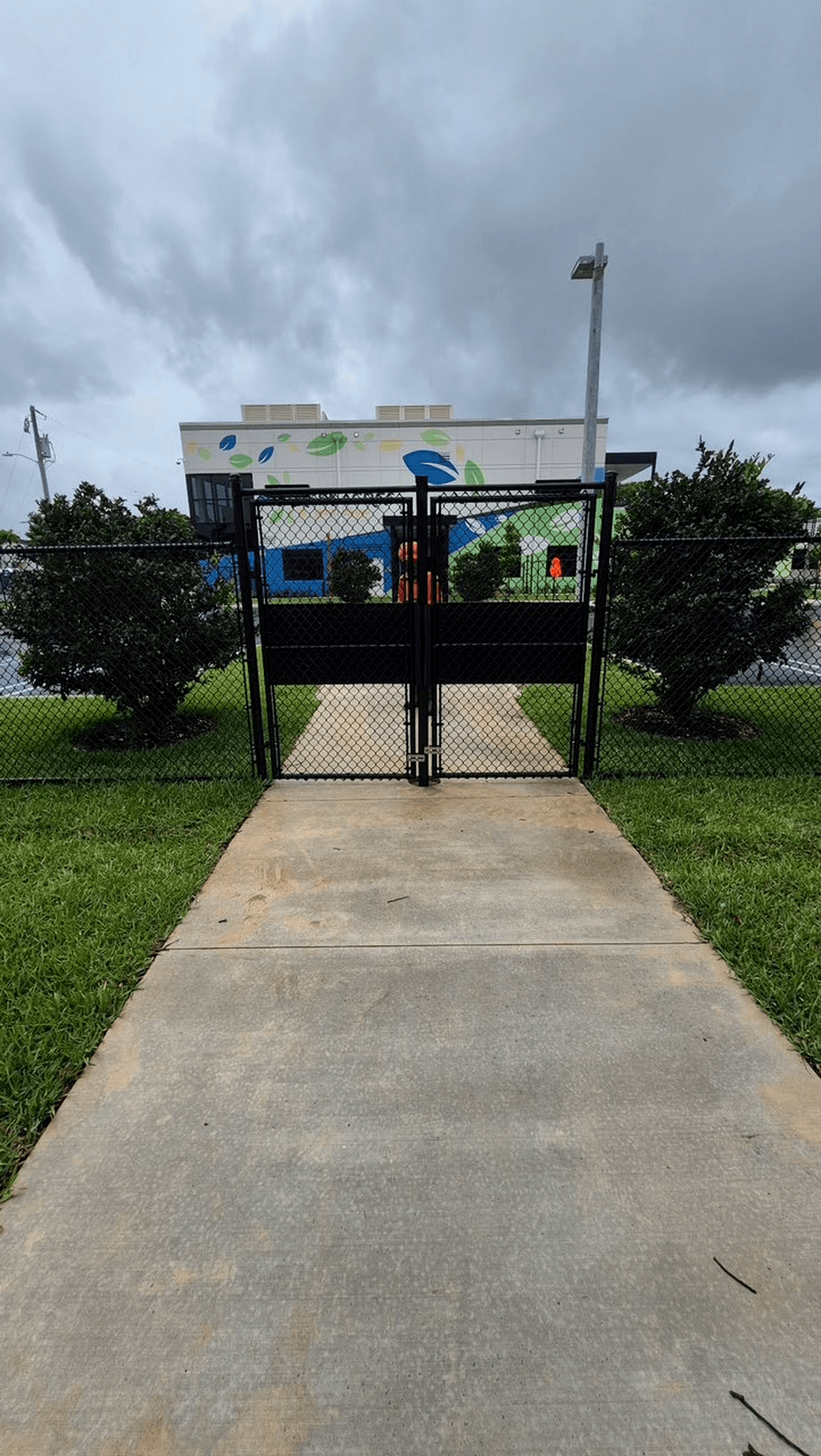 Black vinyl chain-link double swing gate with privacy panels at a commercial entrance
